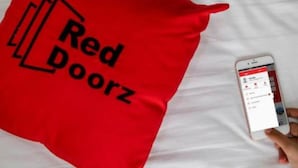 Un coixí vermell amb el text "Red Doorz" sobre un fons blanc.