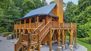 Eine Holzhütte mit blauem Dach, einer Holzterrasse und einem Steinfundament.