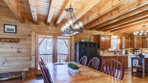 Ein Interieur einer Holzhütte mit Esstisch, Stühlen, einer Küchenzeile und einer Treppe.