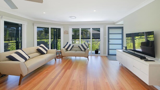 A spacious living room with a large TV, two sofas, and a wooden floor. - Sunny Time - Avoca Beach (Avoca)