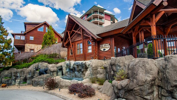 Un edificio de estilo cabaña de troncos con fachada de piedra, un balcón y un letrero que dice "Big Bear Lodge & Resort".