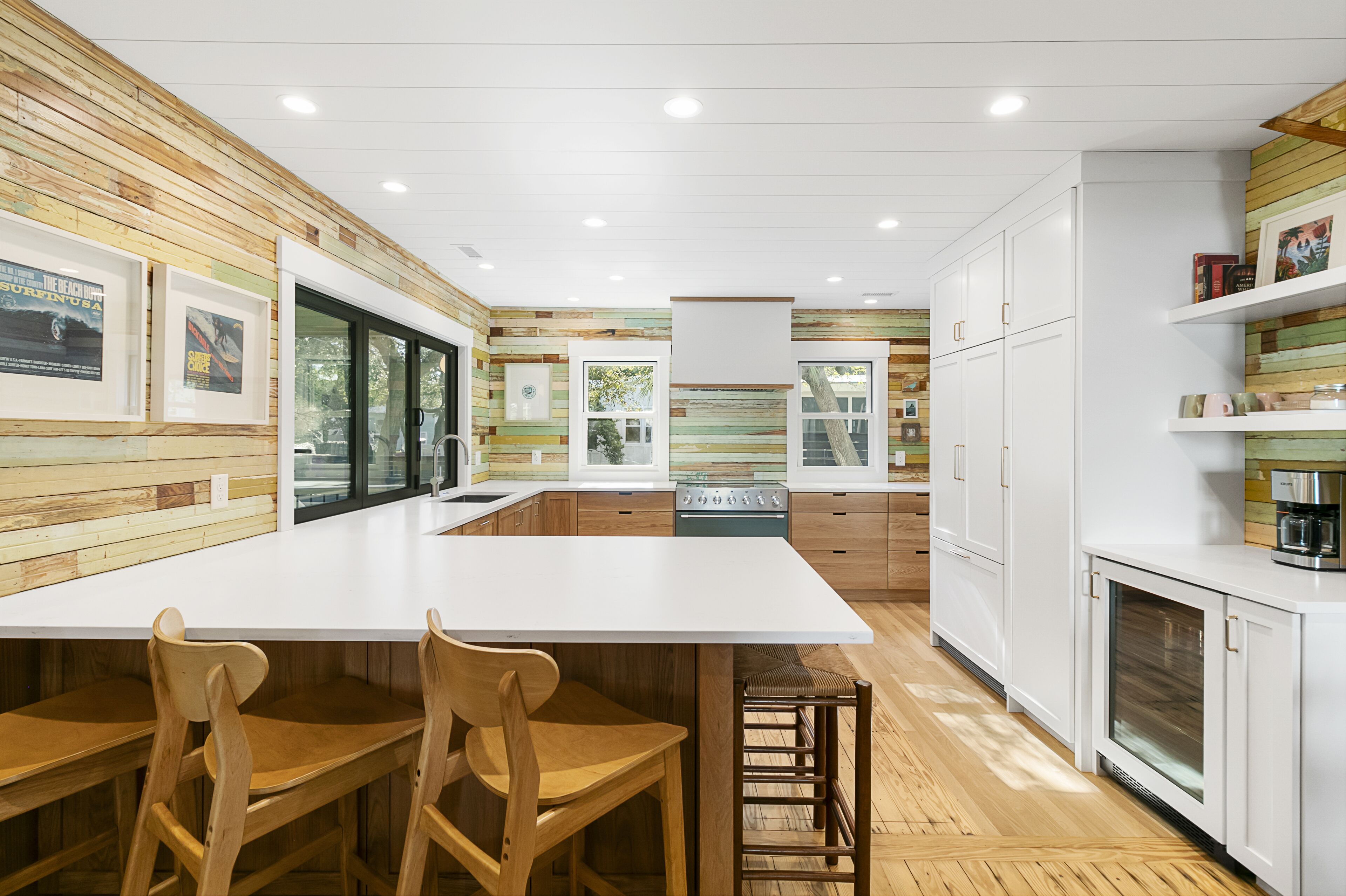 A modern kitchen with wooden accents, white cabinetry, and a large island with bar stools.