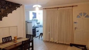 Un comedor con mesa y sillas, una cocina al fondo y una puerta con ventanal.