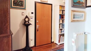 Ein Flur mit einer Holztür, einem Bücherregal, einer Uhr und gerahmten Kunstwerken an den Wänden.