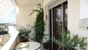 Ein Balkon mit Tisch, Blumentöpfen, Toilette und einer Schiebeglastür.