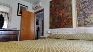 Ein Schlafzimmer mit Bett, Kommode, Spiegel und Bildern an den Wänden.