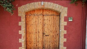 Eine Holztür mit Ziegelbogen, eine rote Wand und ein Schild mit den Buchstaben "TR".