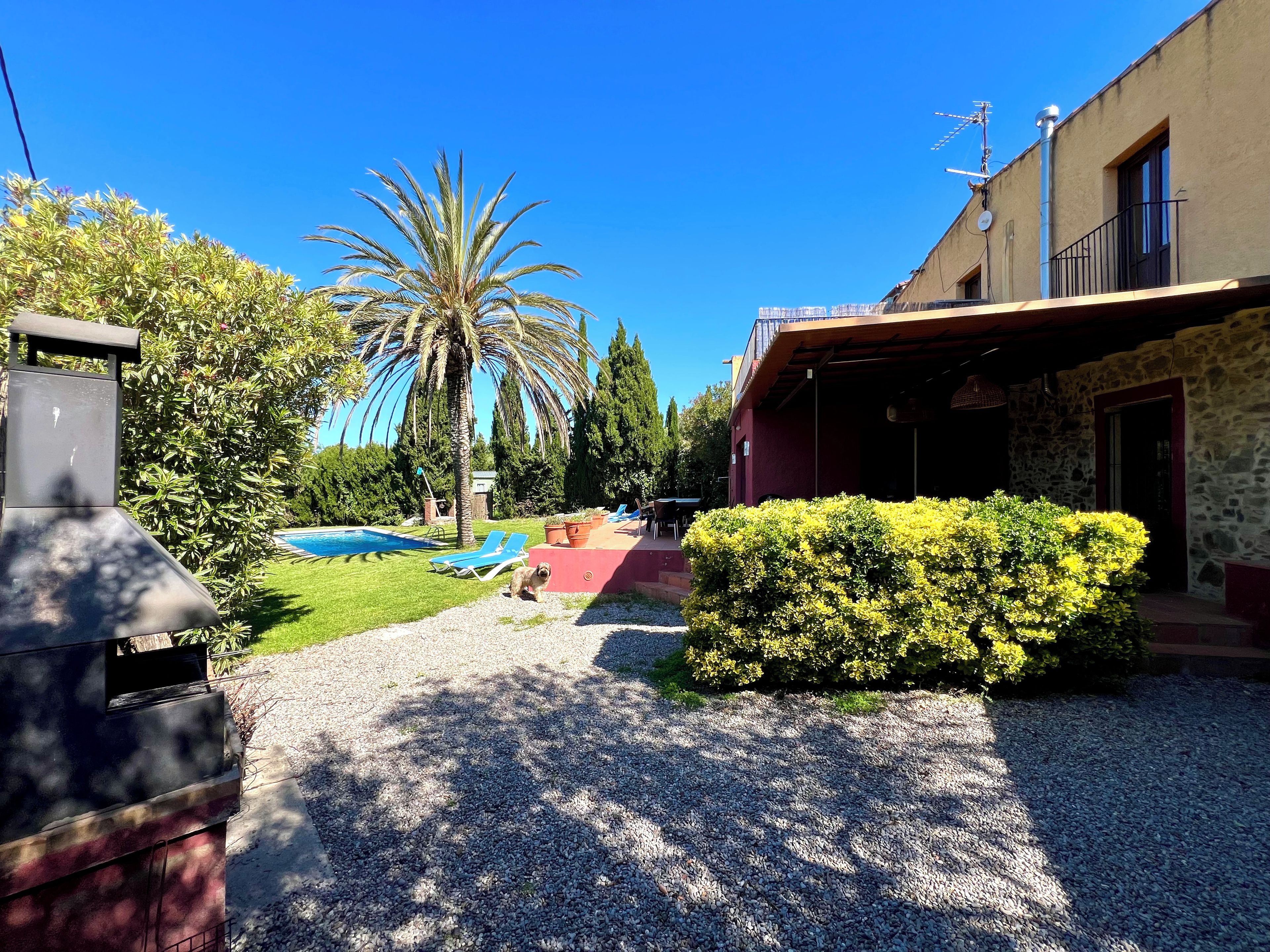 A residential area with a swimming pool, a barbecue grill, and a stone building.
