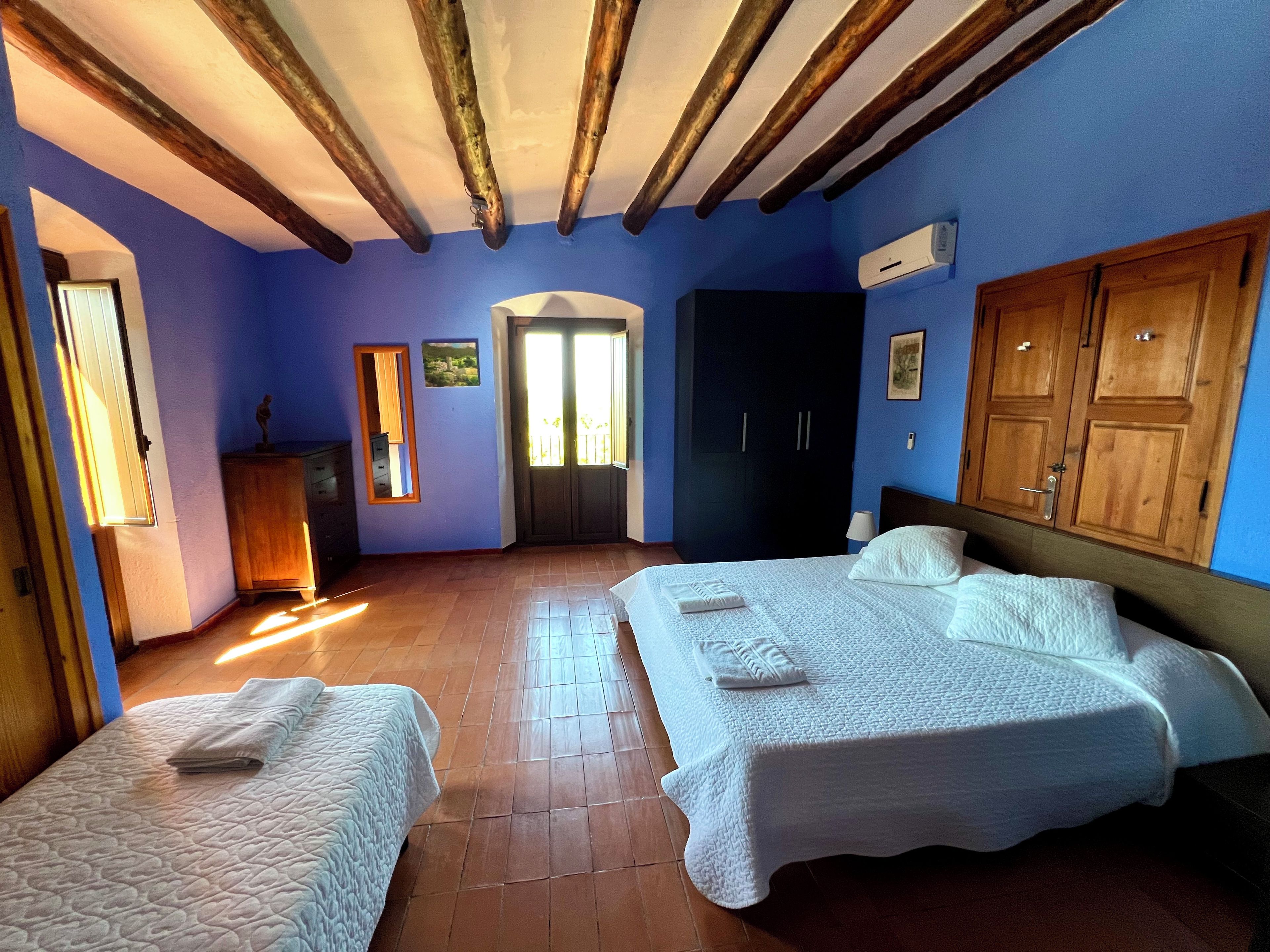 A room with two beds, a wardrobe, a mirror, and a door.