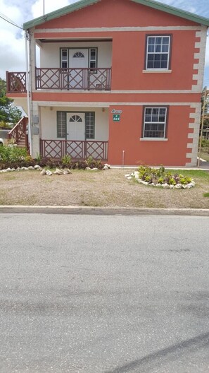 A two-story building with a balcony on the upper floor. - Breezy Apts (Four Roads)