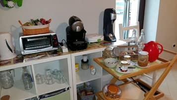 A kitchenette with a toaster, coffee maker, and various food items on the counter.