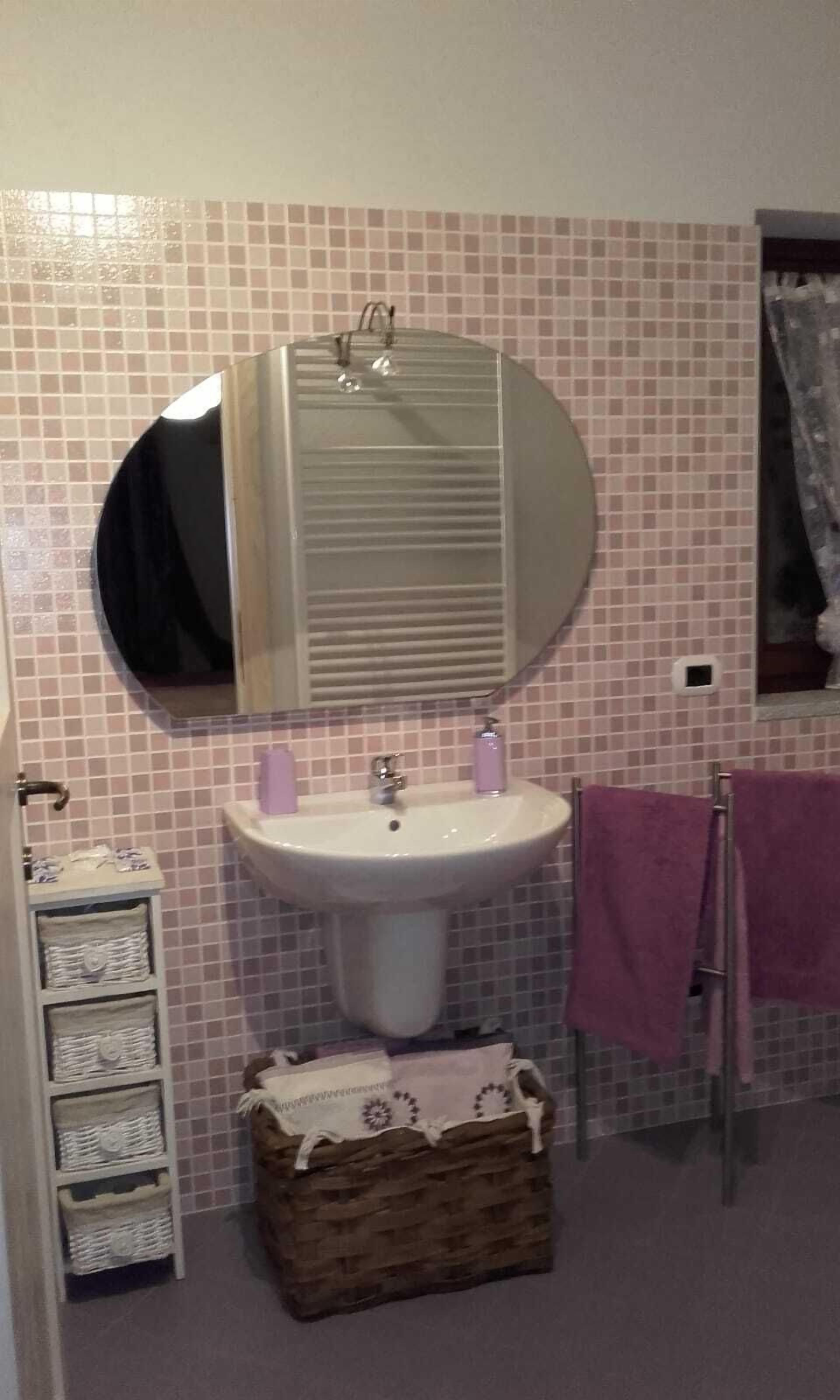 Un baño con lavamanos, espejo y paredes con azulejos.