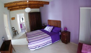 Un dormitorio con cama, cabecero de madera, mesita de noche y ventana con persianas.