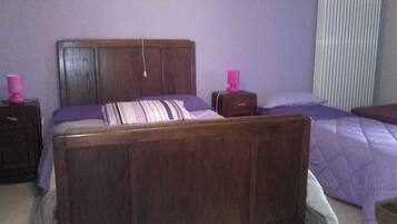 Una cama de madera con cabecera, una mesita de noche y una mesilla.
