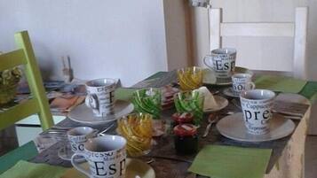 Una mesa de comedor con varias tazas de café y un frasco pequeño de mermelada.