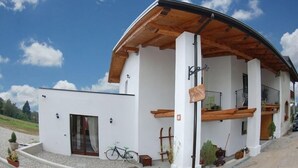 Un edificio moderno con fachada blanca, vigas de madera y un porche cubierto.