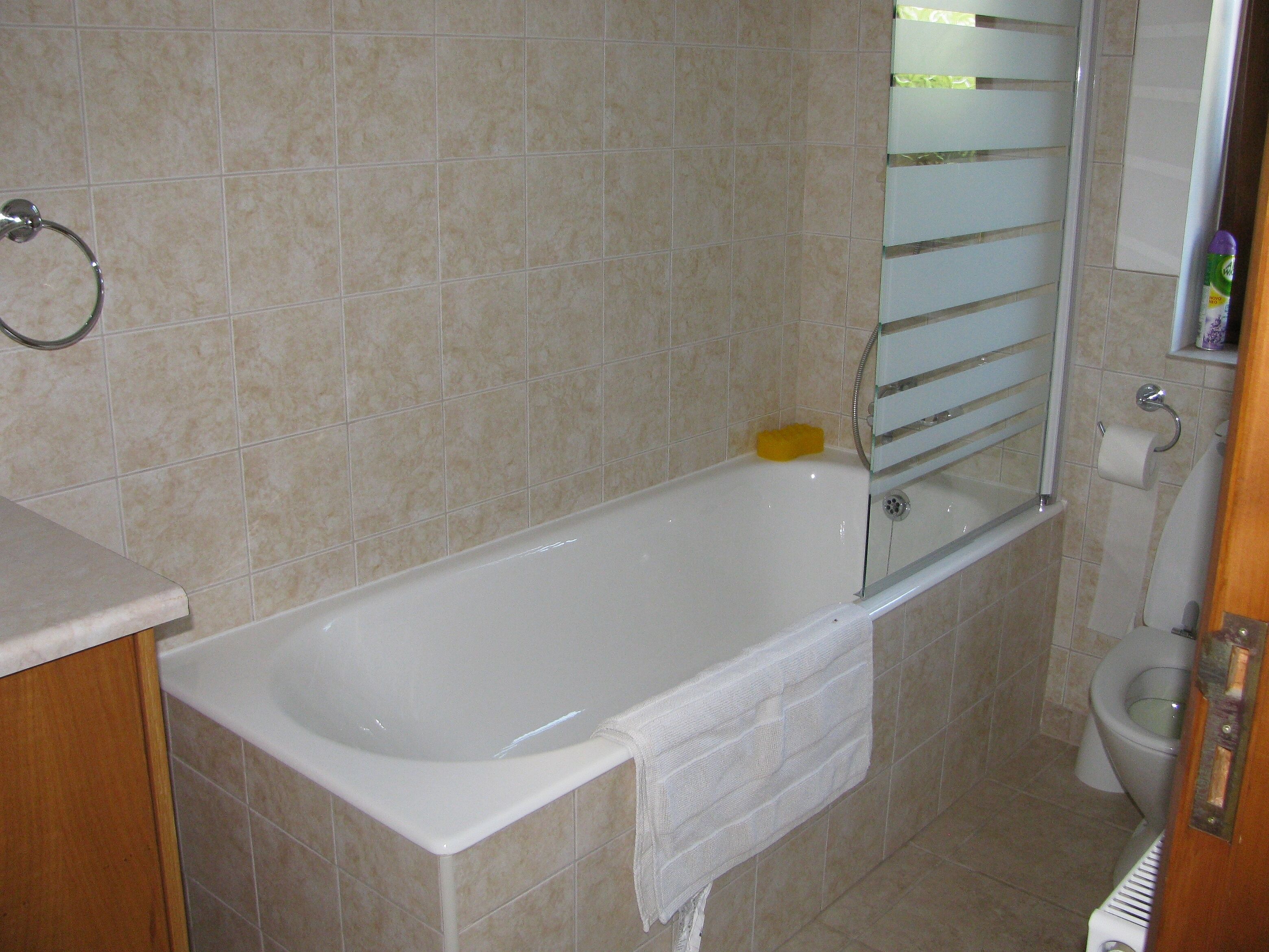 A bathroom with a bathtub, toilet, and a mirror.
