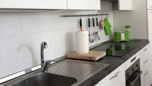 A modern kitchen with white cabinets, a stainless steel sink, and a black countertop.