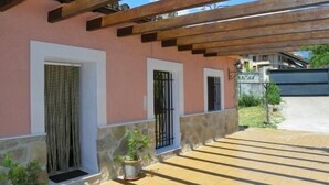 Un espacio al aire libre cubierto con un muro de piedra, plantas en macetas y un suelo de baldosas que conduce a la entrada de un edificio.