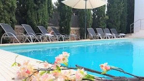 Ein Poolbereich mit Liegestühlen und einer gefliesten Terrasse.