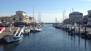 Un port de plaisance avec des bateaux amarrés le long de la rive, des bâtiments sur la côte et un ciel dégagé.