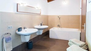 Een moderne badkamer met twee wastafels, een bad en een spiegel boven de wastafels.
