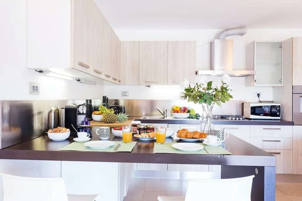 Une cuisine moderne dotée d’un îlot central, d’appareils électroménagers en acier inoxydable et d’un four à micro-ondes.