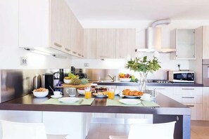 A modern kitchen with a central island, stainless steel appliances, and a microwave. - Stunning Italian Lakes villa with lake views (Dumenza)