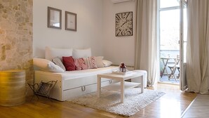 A modern living room with a stone wall, white sofa, and a view to the outside.