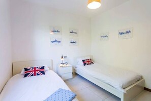A hotel room with two beds, a nightstand, a lamp, and wall art. - Family friendly Italian Lakes villa rental (Dumenza)
