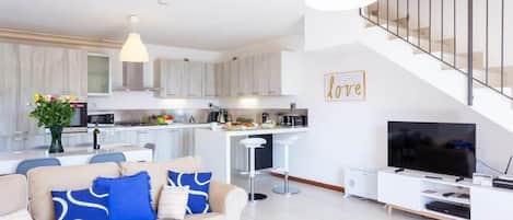 A modern apartment with a living room, kitchen, and a staircase.