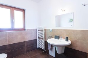 Une salle de bain avec un lavabo blanc, un porte-serviettes et une fenêtre.