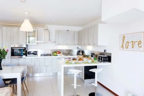A modern kitchen with white cabinetry, a central island with stools, and a pendant light. - Family friendly Italian Lakes villa rental (Dumenza)