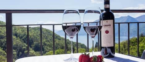 A table with two wine glasses and a bottle of Chianti wine, set against a scenic mountain backdrop.