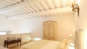 Una camera da letto con un letto, un comodino, una lampada, un armadio e una panca.