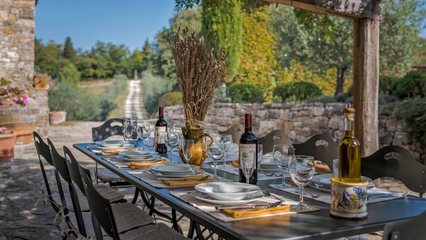 Ett utomhusområde med plats för måltider, en stenmur, en pergola och fri utsikt över en trädgårdsgång.