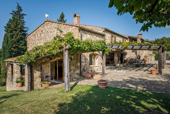 A stone building with a covered patio and potted plants.