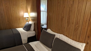 A room with two beds, wooden walls, a nightstand with a lamp, and a window with curtains. - Lakeview Motel (Lake Isabella)
