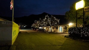 A motel with a single-story structure, a parking area, and a mountain in the background. - Lakeview Motel (Lake Isabella)
