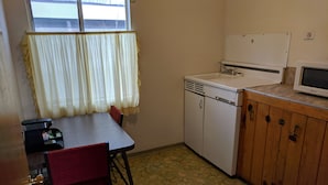 A compact kitchen with a dining table, chairs, a refrigerator, and a microwave. - Lakeview Motel (Lake Isabella)
