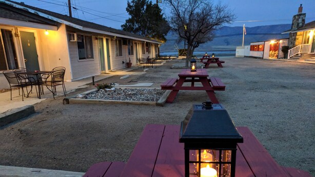 A rustic outdoor seating area with a wooden table and benches, a lantern, and a building in the background. - Lakeview Motel (Lake Isabella)