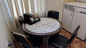 A small kitchen with a round marble table, black chairs, a coffee maker, and a white sink. - Lakeview Motel (Lake Isabella)