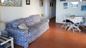 A living room with a patterned sofa, a dining table with chairs, and artwork on the walls. - Casa Pozzillo: two rooms with splendid sea right in front of the house! (Acireale)