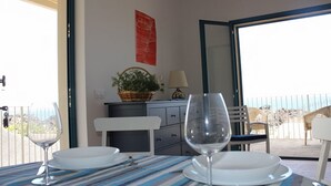 A balcony with a dining table set for two, a potted plant, and a lamp. - Casa Pozzillo: two rooms with splendid sea right in front of the house! (Acireale)