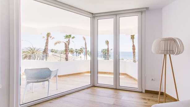 A balcony with a view of the beach, a chair, and a floor lamp. - CRUISE APARTAMENT. First line beach. It will look like it's on a boat. (Málaga)