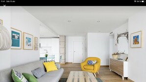 A modern living room with a grey sofa, yellow armchair, and a glass coffee table. - CRUISE APARTAMENT. First line beach. It will look like it's on a boat. (Málaga)