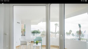 A modern balcony with a view of palm trees and buildings. - CRUISE APARTAMENT. First line beach. It will look like it's on a boat. (Málaga)