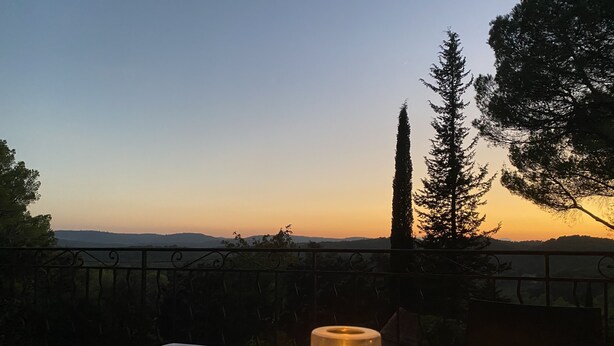A candle on a table with a view of a sunset and trees in the background. - SUPERB SECLUDED VILLA WITH STUNNING VIEWS AND HEATED SWIMMING POOL 
 (Saint-Antonin-Du-Var)