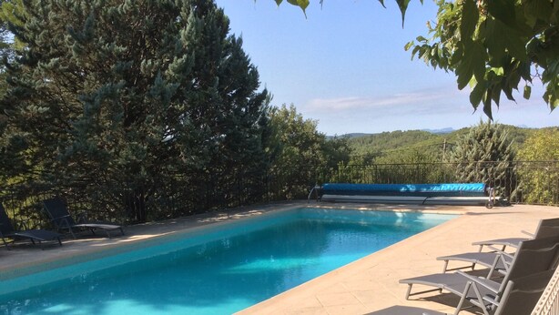 Ein Swimmingpool mit klarem, blauem Wasser, umgeben von Liegestühlen und Bäumen.