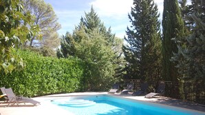 Ein Pool mit Liegestühlen und einer Hecke.
